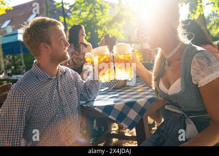 La gente si diverse a mangiare e bere nella birreria bavarese in una giornata di sole Foto Stock