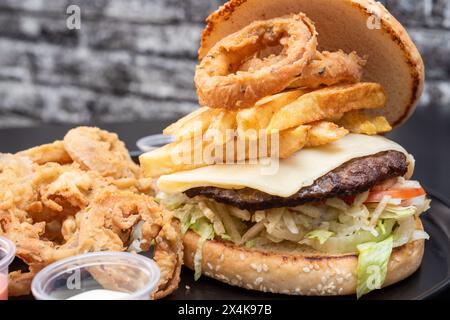 Panino con burguer al formaggio con patatine fritte su carta con sfondo nero Foto Stock