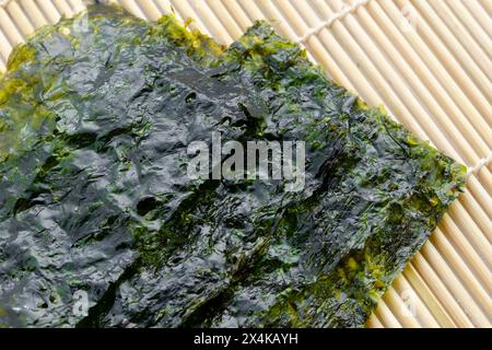 Nori di alghe secche di cucina giapponese con sale su tappetino in bambù. Foto Stock