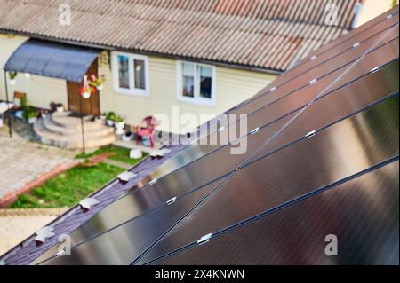 Pannelli solari installati sul tetto inclinato della casa suburbana. Pannelli angolati per catturare la luce solare. Installazione di batterie solari sul tetto della casa. Concetto di fonti energetiche alternative nella vita moderna. Foto Stock