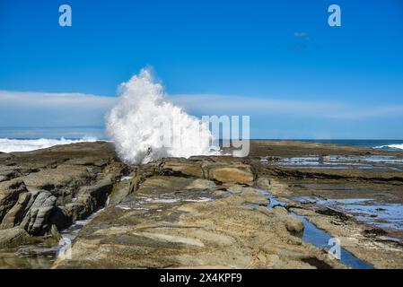 promontorio roccioso con enormi onde che si infrangono Foto Stock