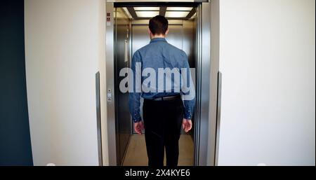 Vista posteriore di Un uomo che utilizza l'ascensore Foto Stock