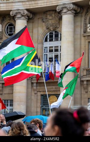 Le bandiere palestinesi, sudafricane e algerine sono sventolate dai manifestanti, mentre le bandiere francesi ed europee appendono su un edificio nelle vicinanze durante una protesta pro-Palestina guidata da studenti delle scuole superiori fuori dal Pantheon a Parigi. In segno di solidarietà con la Palestina, gli studenti delle scuole superiori e universitarie francesi si sono riuniti di fronte al Pantheon a Parigi, denunciando le violenze in atto a Gaza e chiedendo la fine di quello che hanno descritto come un genocidio. La pacifica protesta pro-palestinese è stata accolta con la presenza della polizia antisommossa, che ha anche gestito una vicina contro-protesta pro-Israele. Bandiere, cartelli, Foto Stock