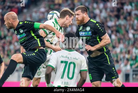 Budapest, Ungheria – 11 maggio 2022. Il centrocampista del Ferencvaros Kristoffer Zachariassen in testa con il centrocampista dei Paks Janos Szabo e l'attaccante Martin Adam du Foto Stock