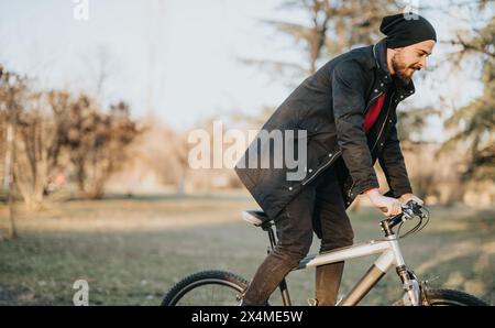 L'uomo ama una piacevole passeggiata in bicicletta attraverso un parco lussureggiante in un pomeriggio di sole Foto Stock