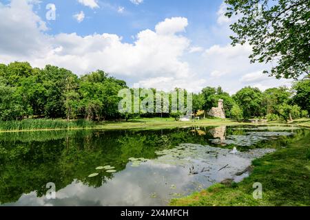 Paesaggio vivido nel parco Nicolae Romaescu da Craiova nella contea di Dolj, Romania, con lago, lillie d'acqua e grandi tres verdi in una splendida sprina soleggiata Foto Stock