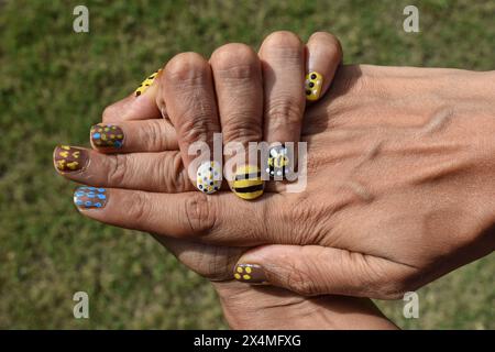 Creative Nail Art con tema Bee. Disegni per unghie, disegni per alveare con strisce, motivi a puntini sui colori giallo, bianco e nero Foto Stock