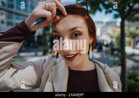 Giovane donna sicura di sé con un sorriso affascinante in un ambiente urbano Foto Stock
