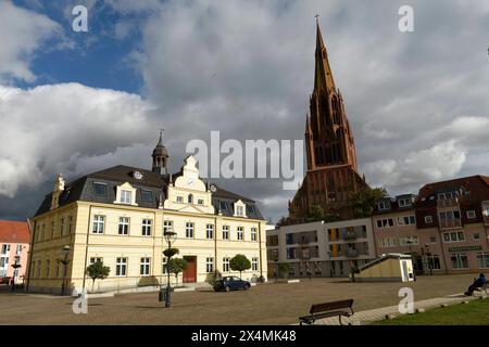 Der Marktplatz, das Demminer Rathaus und dahinter die St.-Bartholomaei-Kirche wird bei einem wolkigen Himmel durch die Sonne besonders angeleuchtet. *** La piazza del mercato, il municipio di Demmin e la chiesa di San Bartolomeo dietro di essa sono illuminati dal sole in un cielo nuvoloso Foto Stock