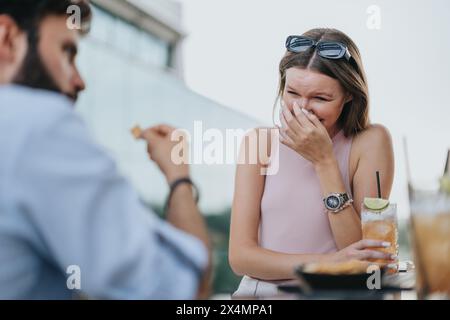 Giovani uomini d'affari che si divertono a conversare e a ridere mentre lavorano insieme in remoto in città al moderno bar urbano. Foto Stock