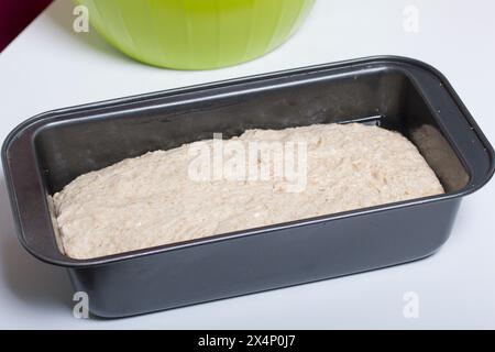 Cuocere il pane a casa. L'impasto integrale si trova nella pentola del pane. Foto Stock