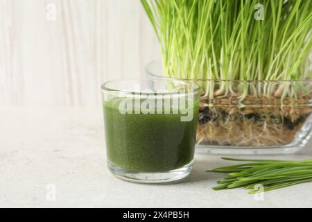 Bere erba di grano in vetro e germogli freschi su un tavolo leggero Foto Stock