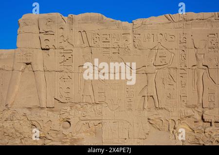 Un rilievo del dio egizio Amon e un faraone con corona bianca (hedjet) presso il complesso del Tempio di Karnak a Luxor, Egitto Foto Stock