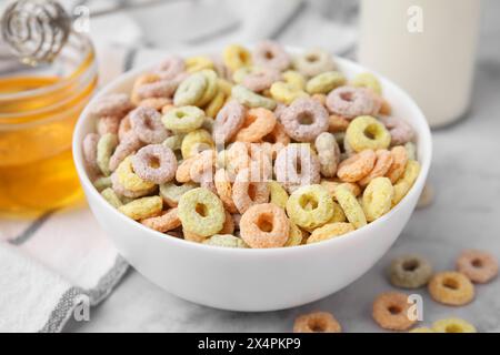 Squisiti anelli di cereali nel recipiente su un tavolo leggero, primo piano Foto Stock