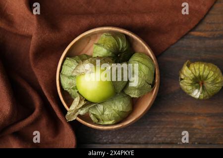 Tomatillo verde fresco con buccia nel recipiente su un tavolo di legno, vista dall'alto Foto Stock