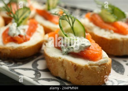 Stuzzichini gustosi con salmone, cetriolo, formaggio spalmabile e aneto sul tavolo, primo piano Foto Stock