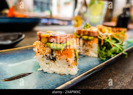 Vista dall'alto del piatto di sushi roll. un appetitoso rotolo su un piatto di ceramica rettangolare blu viene servito su un tavolo in un ristorante Foto Stock