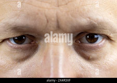 Questa immagine cattura gli occhi marroni e profondi di un uomo di 45 anni. Le rughe e le linee sottili intorno ai suoi occhi raccontano una storia delle esperienze di vita e.. Foto Stock