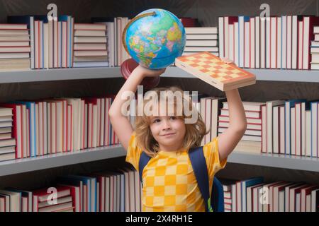 Ragazzo di scuola con globo mondiale e scacchi, infanzia. Studente di scuola che impara in classe, studia la lingua inglese a scuola. Bambino della scuola elementare Foto Stock