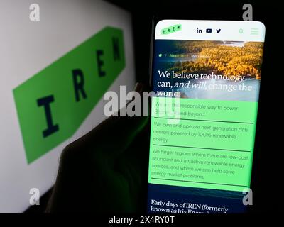 Persona che detiene un cellulare con pagina web della società mineraria australiana di Bitcoin Iris Energy Ltd. (IREN) con logo. Messa a fuoco al centro del display del telefono. Foto Stock