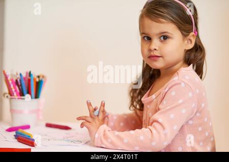 Ritratto, ragazza e colorazione a casa, scrivania e pastelli per lo sviluppo, l'attività e l'arte. Bambino, disegno e istruzione per carta, libri e bambini in età prescolare Foto Stock