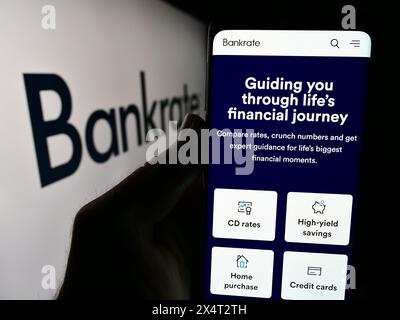 Persona che detiene un cellulare con la pagina web della società di finanziamento al consumo statunitense Bankrate LLC davanti al logo aziendale. Messa a fuoco al centro del display del telefono. Foto Stock