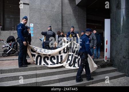 4 maggio 2024, Bruxelles, Belgio. La polizia ispeziona uno striscione che recita "Stop Fossil Fuels”, trattenendo numerosi giovani manifestanti al di fuori del Parlamento europeo nella sua giornata pubblica di apertura. I manifestanti sono stati poi ammanettati e portati via in un furgone bianco senza marchio. Crediti: Alamy Live News Foto Stock