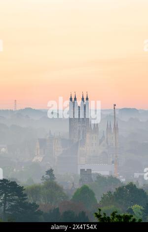 Teleobiettivo della cattedrale di Canterbury illuminata dall'alba (invisibile) nelle prime ore del mattino, in una mattina primaverile. Cattedrale circondata da bassi edifici. Foto Stock