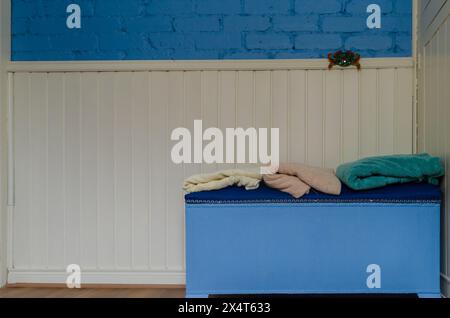 Parete del bagno con mattoni blu e pannelli di legno e un automan e asciugamani piegati sopra Foto Stock