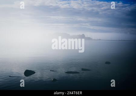 Vista mare con nebbia sul mare la mattina presto di luglio. All'orizzonte, l'isola di Sarkka a malapena visibile. Finlandia, 2022. Foto Stock