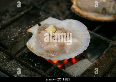 Guscio di pesce e pesce cucinati su una griglia al mercato del pesce di Osaka in Giappone. Foto Stock