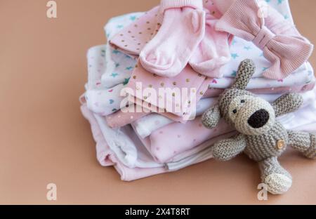 Una pila di tute per neonati. Cucciolo di cane all'uncinetto accanto a una pila di pantaloni per bambini Foto Stock