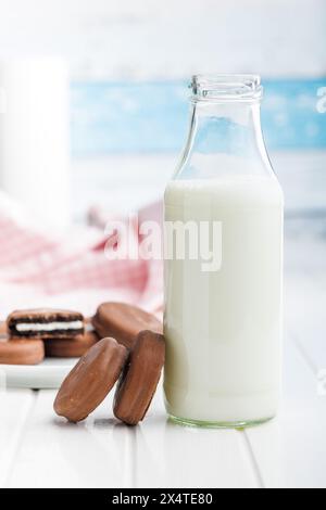 Biscotti ricoperti di cioccolato e bicchiere di latte su un tavolo bianco. Foto Stock