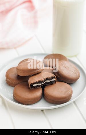 Piatto di biscotti ricoperti di cioccolato e bicchiere di latte Foto Stock