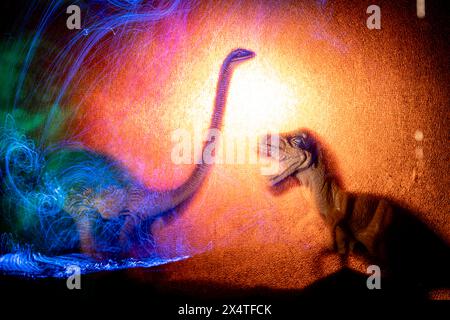 Dinosauri tra le luci. Pittura chiara al buio. Sagome di dinosauro al buio. Foto Stock