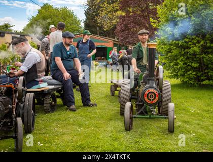 Gli appassionati ammirano un uomo alla guida di un motore di trazione in miniatura alimentato a vapore che tira un rimorchio con il suo cane nero alla South Downs Steam Railway di Pulborou Foto Stock