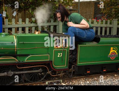 Un volontario guida la locomotiva a vapore miniaturizzata della Railway Mission e il suo tender per il carbone presso la South Downs Light Railway, Pulborough, Regno Unito Foto Stock