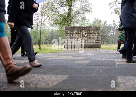 Lohheide, Germania. 5 maggio 2024. I visitatori passano davanti a un muro di pietra con le parole "Bergen-Belsen, 1940-1945" sul terreno del Memoriale di Bergen-Belsen. Nell'aprile 1945, le truppe britanniche liberarono il campo di concentramento di Bergen-Belsen, dove morirono oltre 52.000 persone. Credito: Michael Matthey/dpa/Alamy Live News Foto Stock