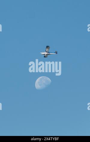 L'aereo vola vicino alla luna contro il cielo azzurro Foto Stock