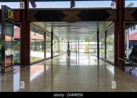 L'uomo cammina verso il gate D6 per imbarcarsi all'aeroporto. Terminal Trek Foto Stock