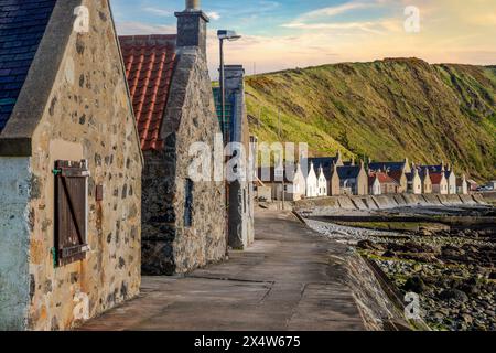 Crovie, un piccolo villaggio di pescatori dell'Aberdeenshire, si aggrappa a una stretta sporgenza tra il mare e le scogliere torreggianti, creando una scena unica e pittoresca. Foto Stock