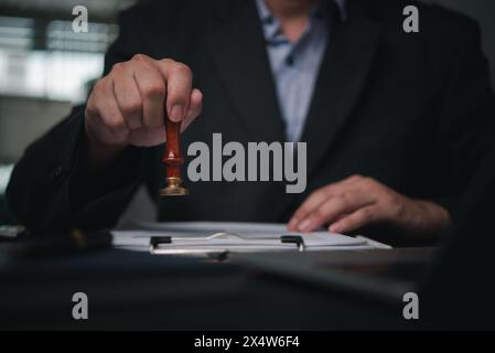la mano sta premendo sigillo su un documento, che significa riservatezza e timbratura approvazione di attività finanziarie bancarie o investimenti di un accordo. Foto Stock