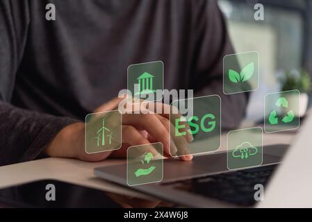 Una persona interagisce con un'interfaccia digitale che mostra icone relative ai principi ESG (Environmental, Social, Governance). Foto Stock