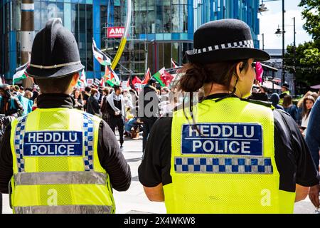 Due agenti di polizia che guardano un manifestante pro-palestinese in una manifestazione di strada anti-Israele - campagna di solidarietà palestinese. Centro di Cardiff. Foto Stock