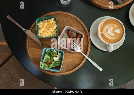 Vista dall'alto delle uova strapazzate con salsiccia, insalata e una tazza di caffè su un tavolo Foto Stock