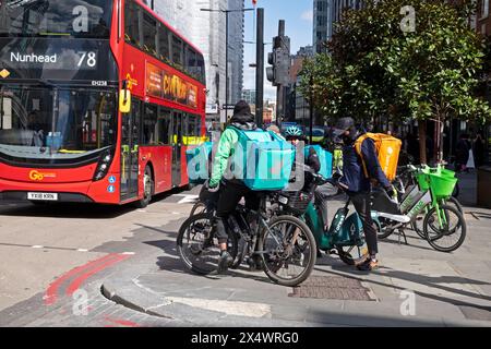 Corrieri lavoratori uomini ciclisti su biciclette per consegna di cibo Liverpool Street Londra Inghilterra Regno Unito 2024 KATHY DEWITT Foto Stock