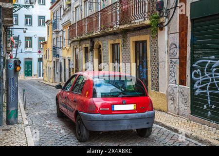 LISBONA, PORTOGALLO - 7 APRILE 2024: Divertente e tipica situazione del traffico a Lisbona. Una piccola auto si ferma a un piccolo semaforo in una stradina. Foto Stock