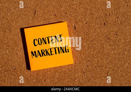 Parole di marketing sui contenuti scritte su un adesivo di carta arancione con sfondo marrone. Simbolo di marketing dei contenuti concettuali. Copia spazio. Foto Stock