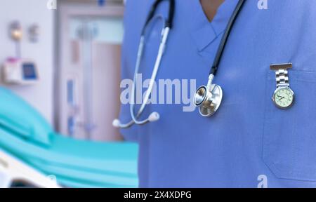 Infermiera in scrub, indossando infermiera orologio FOB e stetoscopio , stanza ospedale sullo sfondo Foto Stock