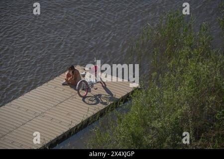 Varsavia, Polonia. 5 maggio 2024. Una donna con una bicicletta viene vista su un molo di legno durante il clima eccezionalmente caldo e soleggiato a Varsavia, in Polonia, il 5 maggio 2024. La Polonia e l'Europa orientale hanno visto un clima eccezionalmente caldo all'inizio della stagione primaverile con temperature che salgono a quasi 30 gradi Celsius in diverse parti della regione. (Foto di Jaap Arriens/Sipa USA) credito: SIPA USA/Alamy Live News Foto Stock